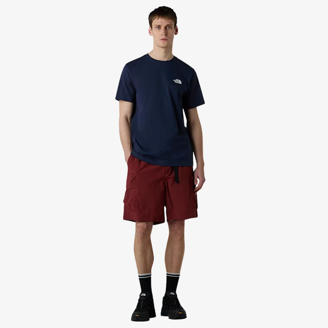 Homme portant un t-shirt simple The North Face bleu avec des shorts rouges, idéal pour le confort quotidien.