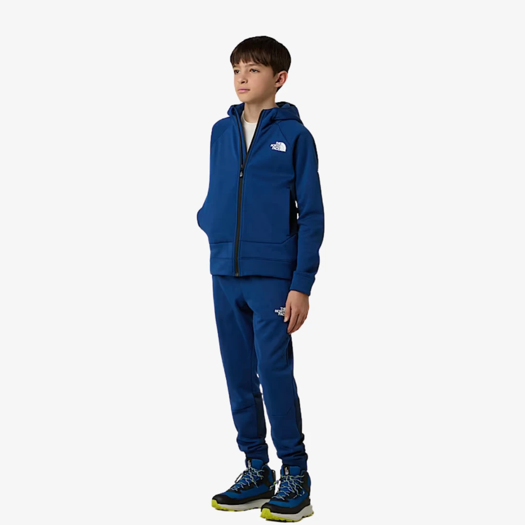 veste de sport zippée North Face portée par un jeune en tenue de sport bleue avec capuche.