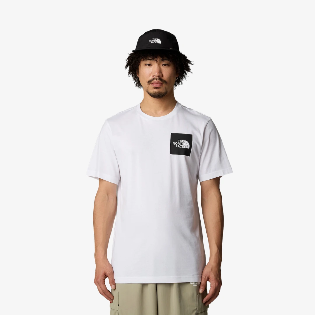 Homme portant un t-shirt North Face confort en blanc, avec un chapeau assorti, affichant un style décontracté.