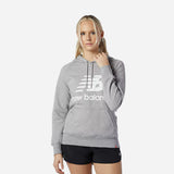 Woman wearing a gray New Balance Essentials pullover hoodie with a large logo, styled for comfort and everyday wear.