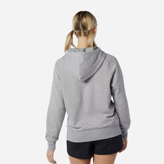 Woman wearing a gray New Balance Essentials pullover hoodie, showcasing the back view and comfortable fit.