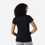 Woman wearing a black New Balance Essentials Stacked Logo Tee from the back, showcasing a casual athletic style.